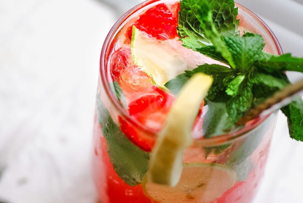 Fresh strawberry lemonade in a glass with lime slices and mint leaves